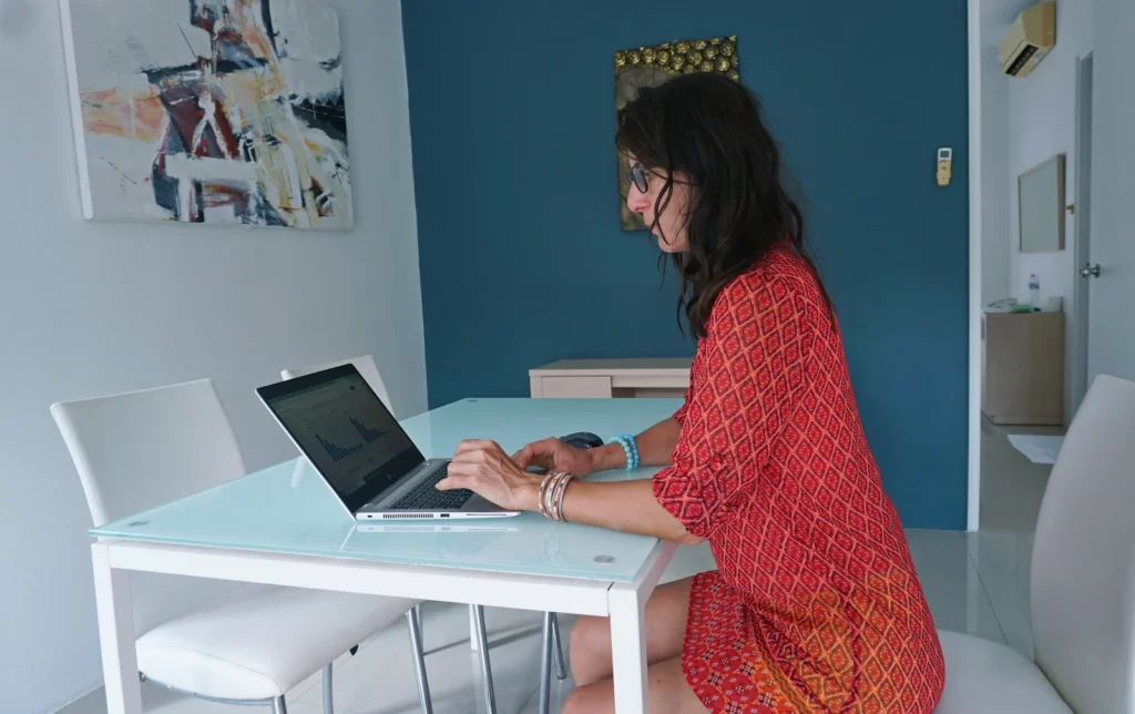 Woman researching on a laptop at a table in a bright room